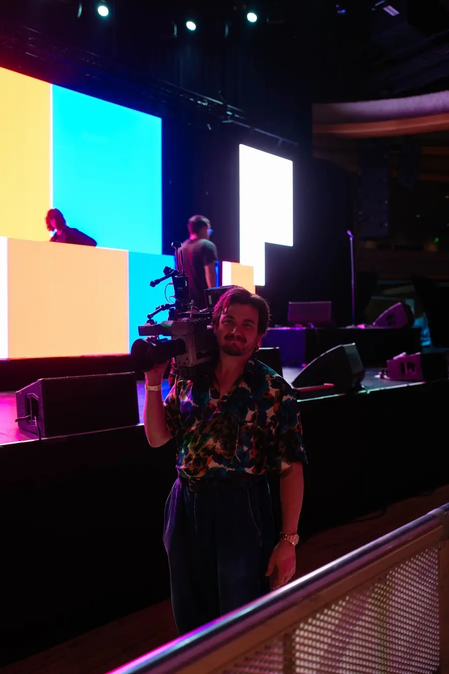 Camera operator on the floor at the Palladium, stage screens behind
