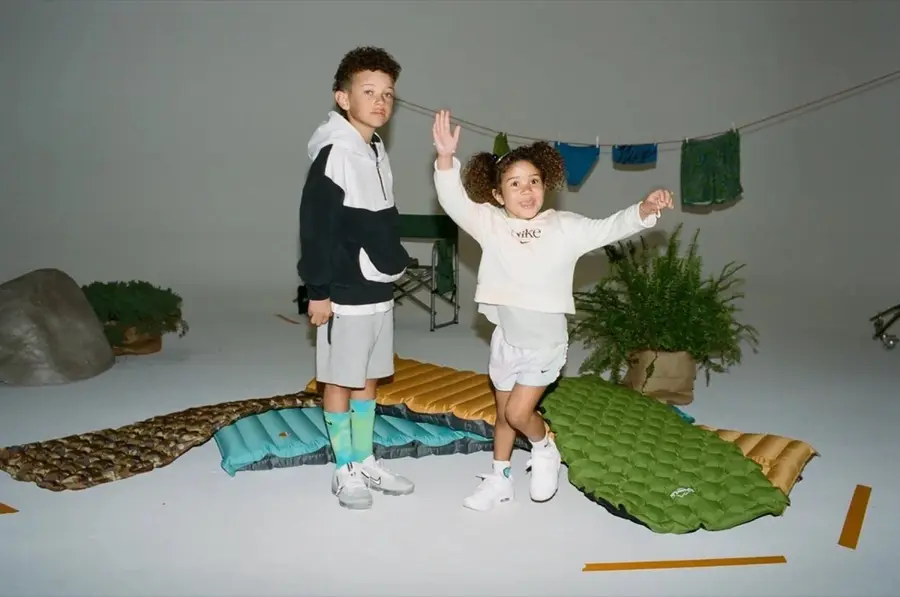 Two kids on inflatable sleeping pads in a Nike studio set
