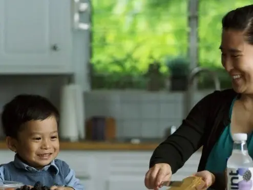 Mother and son smiling in a kitchen with Hint water on the table